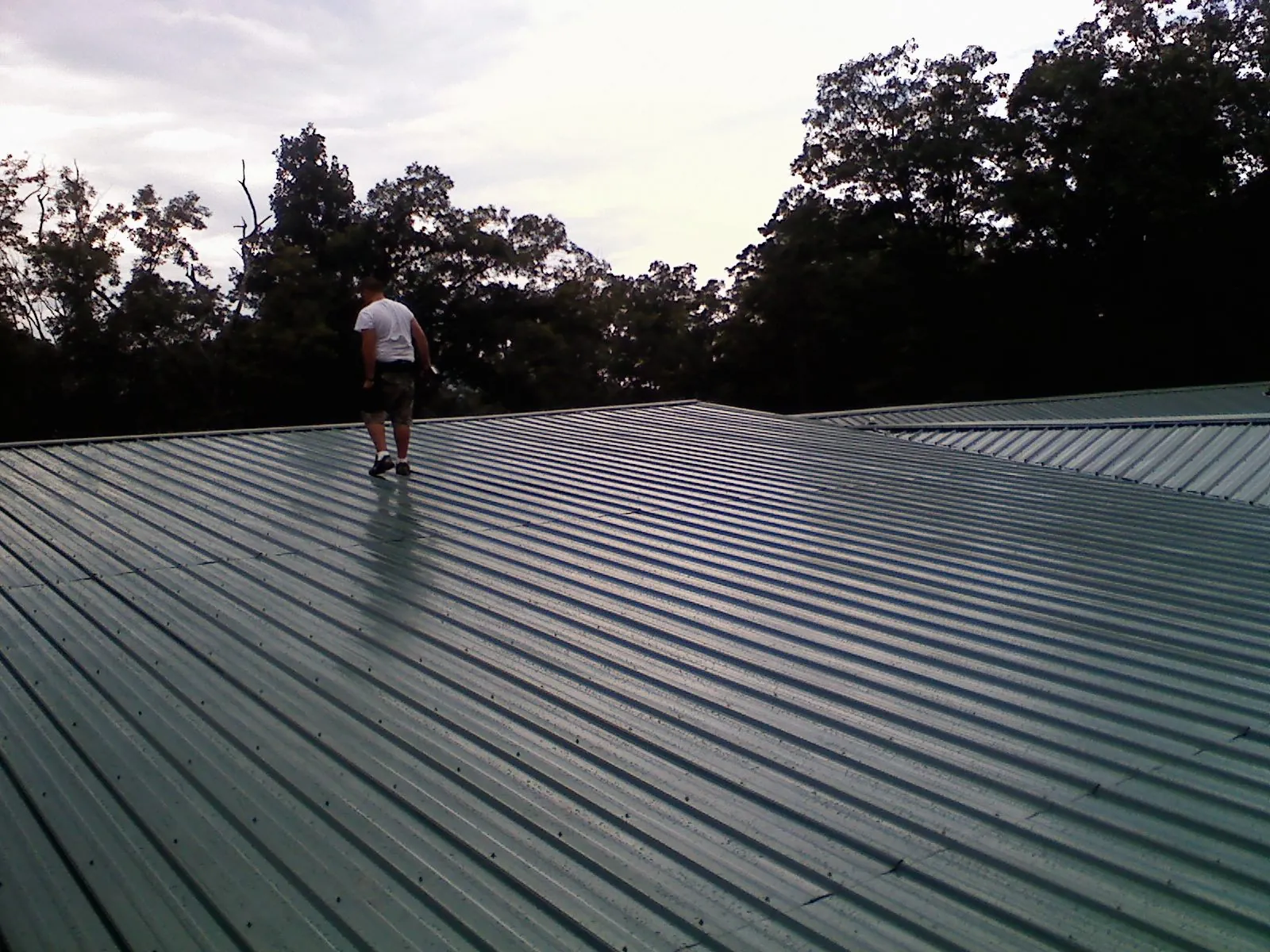 Roofer walking a wide expanse of new green metal roofing in Marion